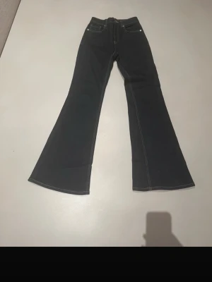 Mörkblå bootcut jeans med kontrastsömmar - Säljer ett par mörkblå bootcut jeans med snygga kontrastsömmar. Jeansen har klassisk femficksdesign och utsvängda ben. Perfekta för dig som gillar en retroinspirerad look och vill ha ett par jeans som sticker ut lite extra. Snygg färg långa i längden och perfekt med klackar eller boots
