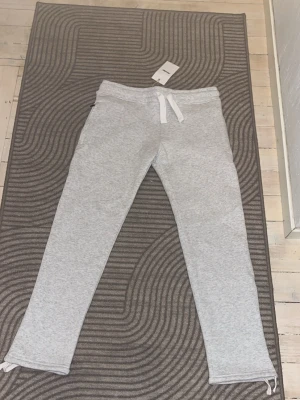 Ljusgrå mjukisbyxor Russmerch XS - Säljer ett par ljusgrå mjukisbyxor från Russmerch i unisexmodell. Byxorna har dragsko i midjan och raka ben. Tillverkade i mjukt material och perfekta för chill dagar. OEKO-TEX certifierade för extra trygghet.