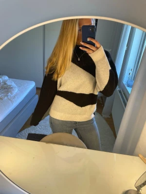 Svartvit stickad tröja med mönster - Säljer en stickad tröja i svart och vitt med breda diagonala blockränder. Tröjan har hög hals, långa ärmar och ribbade muddar vid ärmslut och nederkant. Perfekt för dig som gillar en avslappnad och trendig look. Endast använd ett fåtal gånger. Köptes på cassels för 600kr