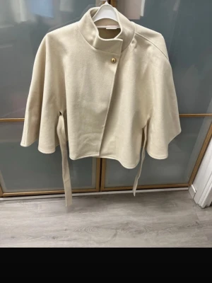 Beige poncho  - Säljer denna snygga ponchon från Nelly eftersom att den tyvärr inte kom till användning då jag hade en svart likadan. Jag har endast använd denna en gång och den är i helt nytt skick. Den har inga märken eller knottror. 