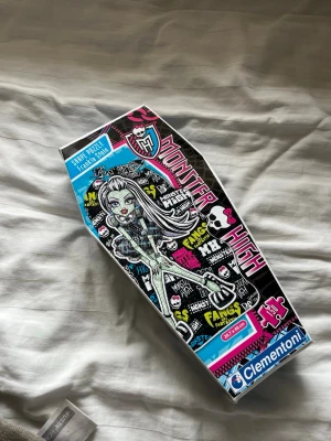 Monster High pussel i kistform - Monster High-pussel från Clementoni i en unik kistformad kartong. Motivet föreställer en av Monster High-karaktärerna Innehåller 104 bitar.