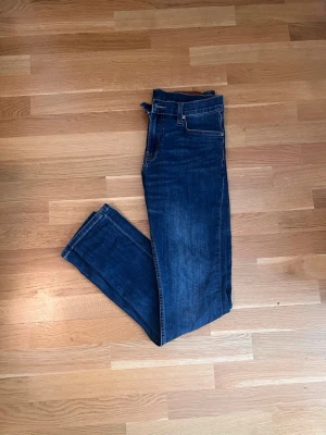 Mörkblå skinny jeans från Lee - Snygga mörkblå skinny jeans från Lee med klassisk femficksdesign och Lee-lapp bak i midjan. Jeansen har smal passform och är tillverkade i stretchigt denimtyg för extra komfort. Perfekta till en avslappnad streetstyle-look. Storlek30/31