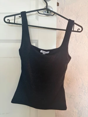 Marinblå glittrig linnetopp från Subdued - Säljer en mörkblå linnetopp från Subdued med glittrigt material. Toppen har breda axelband och en tight passform och en u- ringning. Storlek XS.