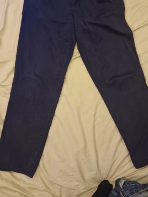 Mörkblå raka chinos från Lee - Säljer ett par mörkblå jeans från Lee med rak passform och klassisk femficksdesign. Jeansen har hög midja och dragkedjegylf. Tillverkade i ett robust denimtyg som passar perfekt till en avslappnad stil.