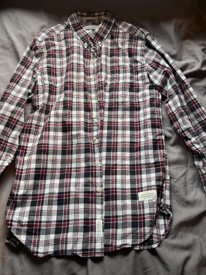 Rutig skjorta från Peak Performance - Snygg rutig skjorta från Peak Performance i vitt, svart och vinrött. Klassisk krage, bröstficka och knappar framtill. Tillverkad i mjuk bomull, perfekt för en avslappnad men ändå stilren look.