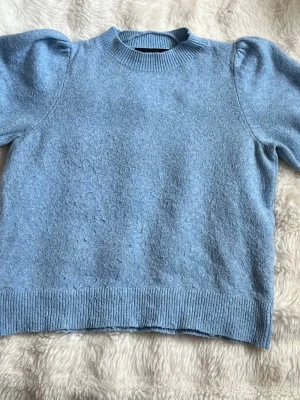 Ljusblå stickad tröja med puffärm - Mysig ljusblå stickad tröja med korta ärmar. Skön att ha en lite kallare sommardag. Det står att den är i storlek S men den passar mig med m i storlek. Tror att den passar både S och m bra  Mått finns på bilderna men hör gärna av dig vid frågor🫶