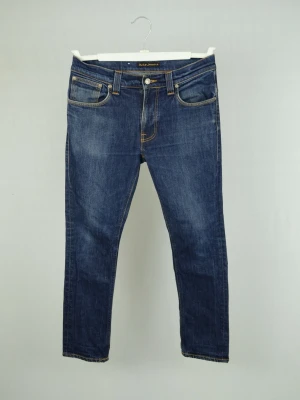 Nudie Jeans  - NUDIE JEANS Storlek : 32/30 Modell : Thin Finn Mått : A = 40CM - B = 97CM Användning : Jeansen är i ett fint skick utan defekter Nypris : Cirka 2000SEK Modellen på bilden : 182CM och väger 78KG