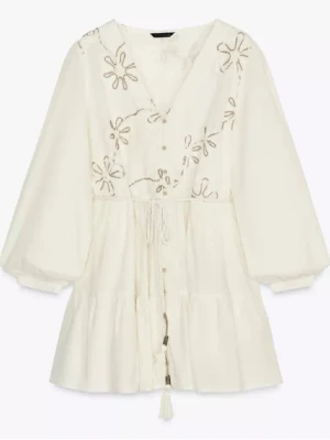 Vit/beige blommig klänning med snörning - Luftig vit klänning i boho-stil med broderade blommor upptill, v-ringning och knytband i midjan. Klänningen har trekvartsärm och volang nedtill, perfekt för sommarens varma dagar. Oanvänd med prislappen kvar, köpt för 399