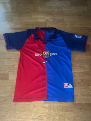 Barcelona jubileumströja Nike - Säljer en riktigt fin ikonisk Barcelona jubileumströja från Nike, med klubbens emblem och årtalen 1899-1999 broderat på bröstet. Rivaldo nr 11 på ryggen! Tröjan är röd och blå med mörkblå ärmar och har en klassisk krage. Perfekt för dig som älskar fotboll och retrostil. Använd 1 gång så i princip nyskick!👍🏼