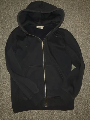 Mörkblå weekday zip - Säljer en svart hoodie från Weekday i storlek XS. Hoodien har dragkedja framtill, stor huva och två fickor på magen. Tillverkad i mjukt material som känns skönt mot huden. Perfekt för en chill och avslappnad stil. Tröjan passar dig från 160-170 och har en riktig snygg passform enligt mig🙌. Har du några frågor är det bara att skriva till mig.