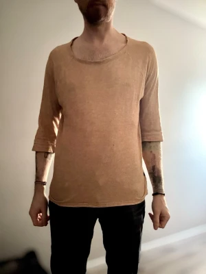 Beige topp med trekvartsärm - En enkel och avslappnad beige topp med trekvartsärm och rund halsringning. Tillverkad i ett mjukt material som känns skönt mot huden. Perfekt för dig som gillar en loose och bekväm stil.