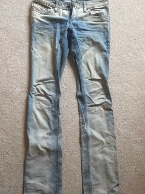 Ljusblå raka lågmidjade jeans från Diesel - Säljer ett par ljusblå bootcut jeans med slitna detaljer och lätt tvättad look från Diesel. Jeansen har låg midja. Perfekta för en avslappnad och trendig stil. 