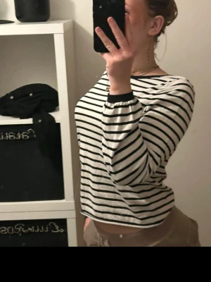 Randig långärmad topp i bomull - Säljer en vit och svart randig långärmad topp med rund halsringning. Toppen har en loose passform och är tillverkad i mjuk bomull, perfekt för en avslappnad stil. Passar till både jeans och kjol.