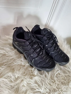 Nike vapormax svarta sneakers - Säljer ett par svarta Nike vapormax, sneakers, med ikoniska vågformade detaljer och synlig Air-sula. Skorna har mesh- och syntetmaterial på ovandelen, samt små Swoosh-loggor på sidan. Grymt sköna och stilrena sneakers med snörning. Endast använda enstaka gånger, inomhus.