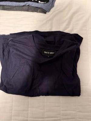 Mörkblå t-shirt från Take Off - En enkel och stilren mörkblå t-shirt från Take Off med klassisk rund hals. Tillverkad i mjuk bomull som känns skön mot huden. Perfekt basplagg att matcha med allt.