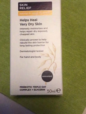 Skin Relief hand- och kroppskräm 50ml - Återfuktande och oparfymerad kräm för mycket torr hud från Skin Relief. Innehåller prebiotiskt trippel havrekomplex och glycerin. Dermatologiskt testad och passar både händer och kropp. Förpackningen är vit med beige detaljer och rymmer 50 ml.