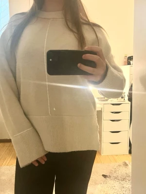 Beige oversized stickad tröja ZARA - Mysig beige stickad tröja med oversized passform och breda ärmar. Tröjan har diskreta sömdetaljer framtill och ribbade muddar vid ärmslut och nederkant.Perfekt för lager på lager och enkel att styla till olika outfits.