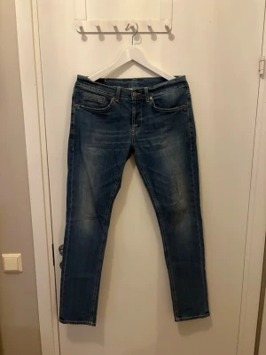 Blå slim fit jeans från Dondup  - Snygga blå slim fit jeans från Dondup Jeans med klassisk femficksmodell och subtila slitningar. Jeansen har orangea sömmar och raka ben. Tillverkade i mjuk denim som ger en skön passform och en avslappnad look.