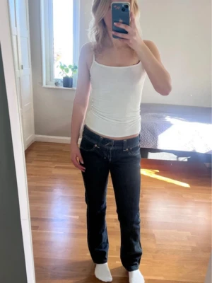 Mörkblå raka jeans från Levi's - Snygga mörkblå bootcut jeans från Levi's med klassiska gula sömmar och femficksmodell. Jeansen har låg midja och en figurnära passform upptill som går ut i lätt utsvängda/raka ben. Perfekta för en trendig och avslappnad look. Säljer då de börjar blir för korta för mig.