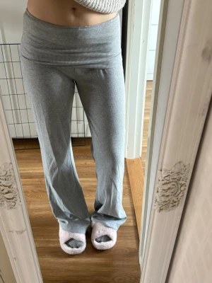 Grå byxor  - Superbekväma grå byxor med bred och ribbad midja. Byxorna har raka ben och är gjorda i ett mjukt och stretchigt material, perfekta för chill dagar hemma. Enkel och stilren design utan synliga loggor eller detaljer.