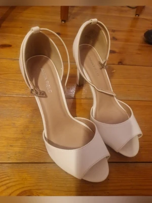 Klackar 37, nyskick - Säljer ett par jättefina och stilrena vita klackskor från Anna Field. Skorna är i storlek 37 och i absolut nyskick, vilket syns tydligt på bilderna.  Detaljer:  Skick: Nyskick, helt rena och oanvända.  Kvalitet: Mycket bekväma klackar från ett populärt märke.   Perfekta för: Dessa skor är det självklara valet för sommarens alla fester, student, bröllop, eller varför inte en utekväll. En tidlös och elegant modell som passar till allt!  