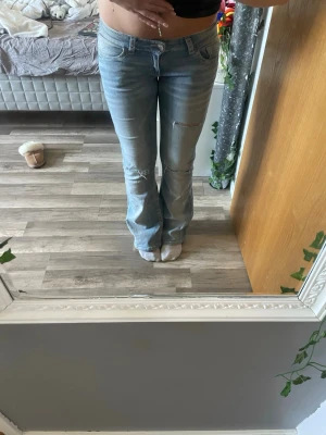 Ljusblå bootcut jeans med slitningar - Säljer ett par ljusblå bootcut jeans med slitningar på låret och knät. Jeansen har klassisk femficksmodell och är tillverkade i denim med lätt stretch. Perfekta för en avslappnad och trendig look. Använda väldigt få gånger.🥰