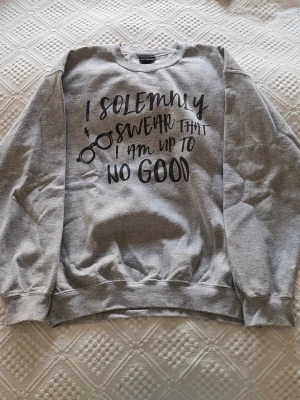 Grå sweatshirt med Harry Potter-tryck - Grå sweatshirt med svart tryck på framsidan där det står 'I solemnly swear that I am up to no good' och en illustration av glasögon. Säljer då den inte kommer till användning längre.
