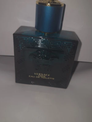 Versace Eros Eau de Toilette - Versace Eros Eau de Toilette i en elegant, fyrkantig flaska av blått glas med guldtext och Medusa-motiv. Flaskan har en stilren blå och guld kork som ger en lyxig känsla. Perfekt för dig som vill ha en ikonisk och kraftfull doft. Cirka 2/3 kvar i den