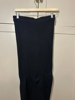 Svart ribbad långkjol från Gina Tricot - Säljer en svart långkjol från Gina Tricot i storlek XS. Kjolen är ribbad och har en enkel, rak passform som är både snygg och bekväm. Kjolen är gjord i ett mjukt och stretchigt material.