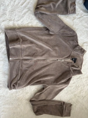 Beige ziphoodie i velour från Amisu - Mjuk och skön beige ziphoodie från Amisu i storlek XS. Tillverkad i velourmaterial med dragkedja framtill och ribbade muddar vid ärmslut och nederkant. Perfekt för en avslappnad och trendig look. Knappt använd, pris kan diskuteras. 