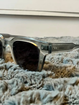 Genomskinliga solglasögon från Chimi - Snygga solglasögon från Chimi med transparent båge och mörka glas. Klassisk fyrkantig form som ger en cool vibe. Kommer med vit hård förvaringsbox, putsduk och tygpåse. Perfekta för soliga dagar och trendiga outfits.