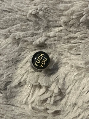 Plug med text i svart och silver - Cool öronplugg i metall med svart front och texten 'FUCK YOU' i gult. Snygg accessoar för dig som vill sticka ut och visa attityd. Passar till töjda hål och har en rund form. 6 MM