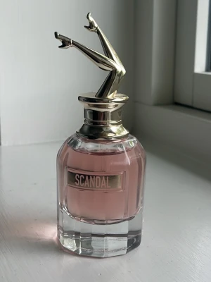 Scandal parfym från Jean Paul Gaultier - Unik parfymflaska med rosa doft från Jean Paul Gaultier, Scandal. Flaskan har en cool design med guldfärgade ben som lock. Har bara användt ett sprut. Skriv för fler frågor o bilder❤️