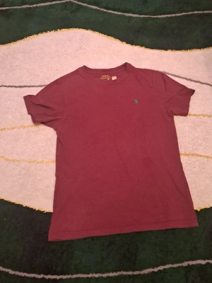 Vinröd t-shirt från Polo Ralph Lauren - Säljer en vinröd t-shirt från Polo Ralph Lauren med klassisk passform och korta ärmar. T-shirten har en liten broderad logga på bröstet och är tillverkad i mjuk bomull. Perfekt för en stilren och avslappnad look.