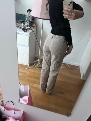 Beige carpenter jeans med raka ben - Säljer ett par snygga beige Carpenter med raka ben och flera fickor på sidorna. Byxorna har hög midja och klassisk cargostil, perfekta för en avslappnad streetlook. Materialet känns mjukt och bekvämt, passar till många olika outfits.