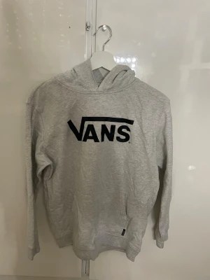 Grå hoodie från Vans med logga - Finns flera fläckar, annars i bra skick. Storlek XL i barnstorlek.