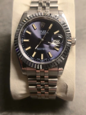 Herrklocka/unisex 36mm jubileelänk  - Snygg och stilren klocka med silverfärgat armband i rostfritt stål och mörkblå urtavla. datumvisning och den klassiska räfflade bezeln. Perfekt accessoar för dig som gillar stilrena detaljer. Jubileet länk. Helt oanvänd! Alla länkar finns! Endast klocka. 