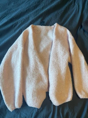 Ljusrosa stickad cardigan - Mysig ljusrosa stickad cardigan med oversized passform och långa ärmar. Öppen framtill utan knäppning, perfekt att slänga på sig över en t-shirt eller topp. Mjuk och fluffig känsla, passar dig som gillar en avslappnad stil. Den rosa färgen framkommer inte rikigt i bilderna💗