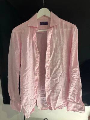 Ljusrosa linneskjorta från Ralph Lauren purple label - Säljer en ljusrosa skjorta från Ralph Lauren Purple Label i svalt linne. Skjortan är ifrån deras mest exklusiva linje som heter ”Purple label”. Skjortan är i suveränt skick och passar mig som är 182 cm och väger 62 kg🙌🙌 Äkthetsbevis finns vid köp!