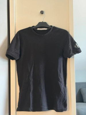 Svart t-shirt från Calvin Klein - En klassisk svart t-shirt från Calvin Klein med rund hals och korta armar. Perfekt basplagg i mjuk bomull som funkar till allt.