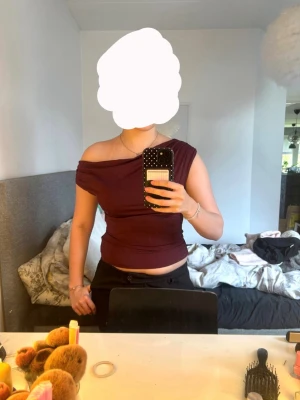 Vinröd topp - Snygg vinröd topp med oneshoulder-design och tight passform. Toppen har en stilren look som passar perfekt till både jeans och kjol. Tillverkad i mjukt material som känns skönt mot huden. Nästan aldrig använd🩷