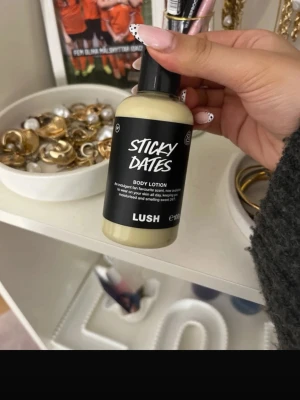 LUSH Sticky Dates Body Lotion - LUSH Sticky Dates Body Lotion med krämig konsistens och söt doft. Kommer i en beige plastflaska med svart etikett och pump. Perfekt för att återfukta huden och lämnar en mjuk känsla. Innehåller 100 ml.