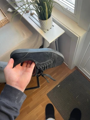 Louboutin  - Snygga svarta sneakers från Christian Louboutin med klassisk röd sula och svarta skosnören. Skorna har en stilren design i mocka och läder, perfekt för dig som gillar exklusiva detaljer och streetstyle. Ikonisk logga på sulan och boxen medföljer ej finns defekter men inga större utifrån