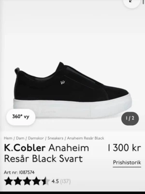 K.Cobler Anaheim svarta sneakers - Svarta slip-on sneakers från K.Cobler, modell Anaheim. Skorna har en stilren design med resår på ovansidan och tjock vit platåsula. Tillverkade i mockaliknande material med diskret logga på sidan. Perfekta för en clean och modern look. Har använt några gånger. Men har rengjort de. Skriv för flera frågor😊