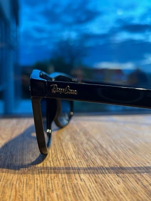 Svarta Ray-Ban boyfriend solglasögon - Klassiska svarta boyfriend solglasögon från Ray-Ban med glansig finish och ikonisk logga på skalmen. Snygg och tidlös design som passar till många olika stilar. Bågarna är i plast och har en fyrkantig form.