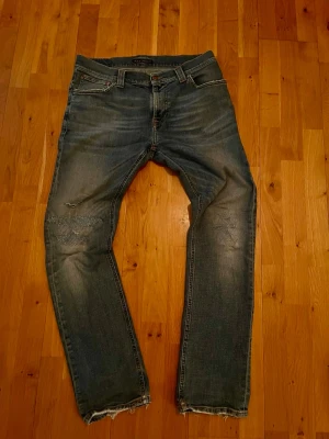 Nudie jeans thin finn - Säljer ett par Nudie Jeans Thin Finn jeans i mörkblå/ljusblå tvätt, storlek W33 L32. Jeans i mycket bra skick utan större slitage. Slim fit-modell med smal passform och klassisk design som passar till allt.  Mått:  * Midja: 42 cm * Längd: 105 cm * Lårbredd: 27 cm * Benöppning: 17 cm  Perfekta vardagsjeans med snygg tvätt och skön passform. Skickas snabbt!