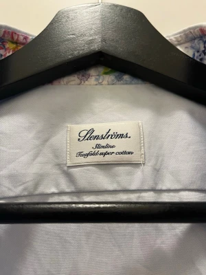Ljusblå slimline skjorta Stenströms - Snygg ljusblå skjorta från Stenströms i slimline-modell. Skjortan är tillverkad i tvåfaldig super cotton och har klassisk krage samt vita knappar. Mycket fint skick