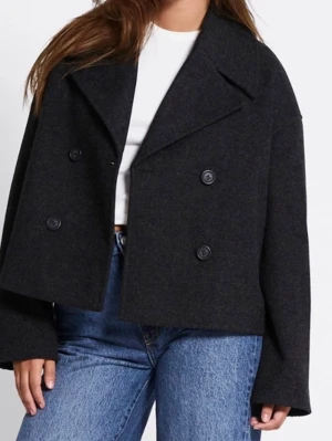 Svart skepparkavaj med dubbelknäppning - Stilren svart skepparkavaj i kort modell med bred krage och dubbelknäppning framtill. Jackan har en boxig passform och är tillverkad i ett ull-liknande material som ger en klassisk look. Perfekt att slänga över en hoodie eller t-shirt. !Använd fåtal gånger! 