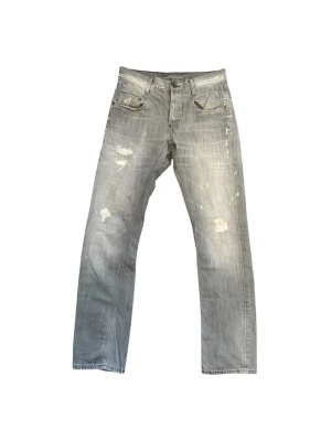 jeans med slitningar  - Säljer ett par grå jeans från G-Star med slitna detaljer och raka ben. Jeansen har klassisk femficksdesign, låg midja och coola slitningar framtill och baktill. Perfekta för en avslappnad och trendig look.