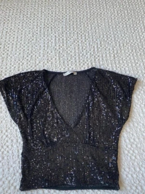 Svart glittrig croppad topp y2k paljett sequin - Snygg svart croppad topp med paljetter och djup v-ringning. Toppen har korta ärmar. Passar XS och S